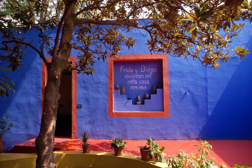 The facade of a Mexican home with blue walls and a painted sign that reads "Frida y Diego vivieron en esta casa 1929 - 1954."