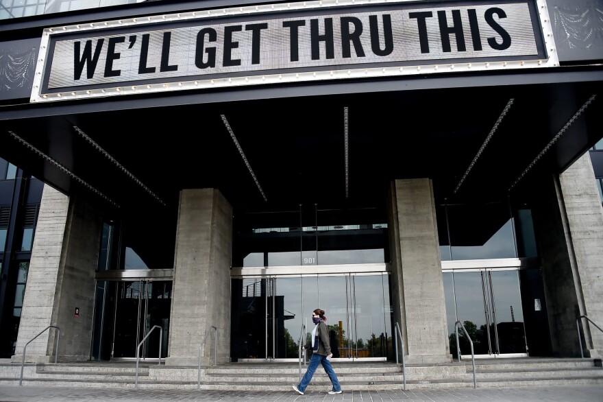 A woman wearing a face mask walks past a sign in front of The Anthem, a popular live music venue, that displays a message of support on their marquee amid the coronavirus pandemic. (Olivier Douliery/AFP via Getty Images)