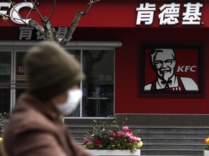 A woman wearing a mask rides past a KFC restaurant in Shanghai last month. Food scares and the bird flu haven't stopped many chicken lovers in the city from visiting KFC and other restaurants.