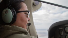 A woman wearing a headset and flying a plane