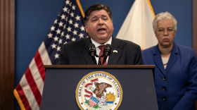 Governor J.B. Pritzker speaking at a podium with Cook County President Toni Preckwinkle standing behind him. Illinois Gov. JB Pritzker and Cook County Board President Toni Preckwinkle discussed legislation to forgive medical debt for Illinoisans in April 2024.