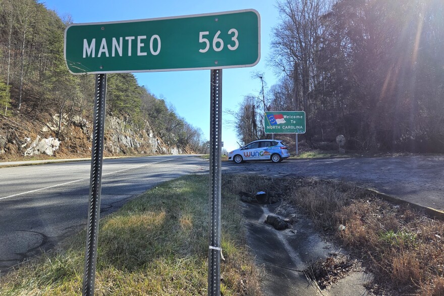 A sign at the western border of North Carolina, where U.S. 64 enters the state from Tennessee, lists the distance to Manteo on the coast. A WUNC vehicle is shown near it on Jan. 11, 2024.