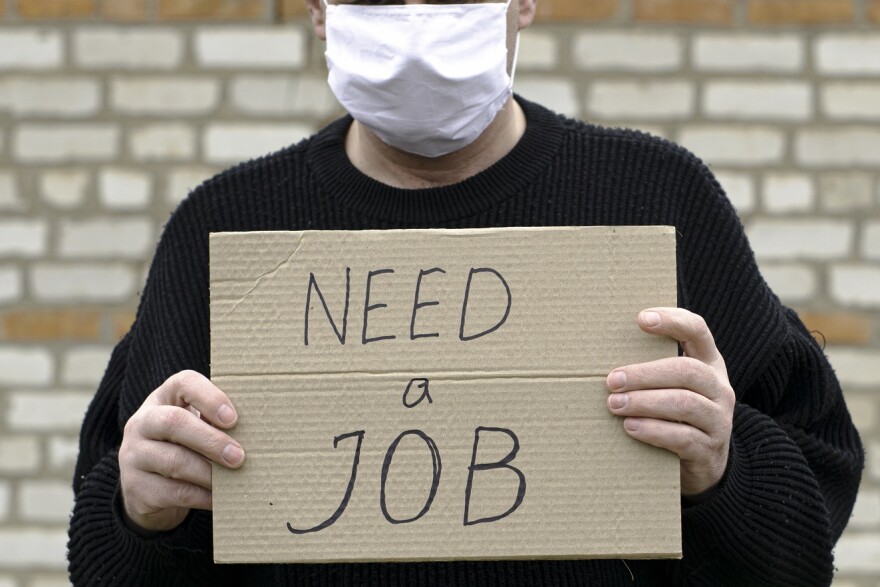  a man in a medical hygienic mask is holding a cardboard tablet with the inscription "need a job"