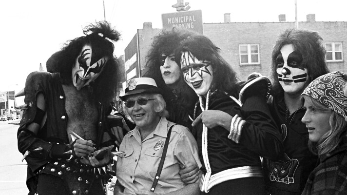 Members of the band KISS pose for a photo with a fan in downtown Cadillac in October 1975.