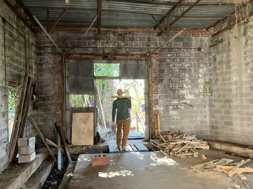 A wood sculpture artist carries some boards.
