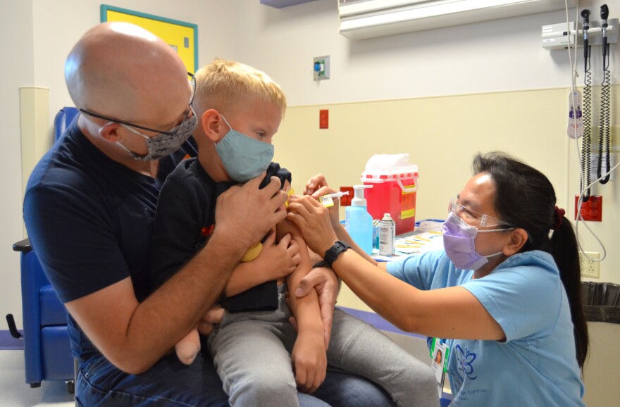 Isaac Mesimer, who's five years old, is held by his father as he get his first dose of the pediatric COVID-19 vaccine.