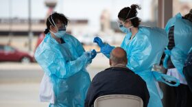 Nurses place a sample taken from a man who is being tested for the coronavirus into a protective tube at a drive-through testing site in Shawnee on April 2.