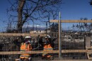 Two workers put up a fence along a residential area destroyed by a deadly wildfire in Lahaina, Hawaiʻi, Saturday, Aug. 19, 2023. (AP Photo/Jae C. Hong)