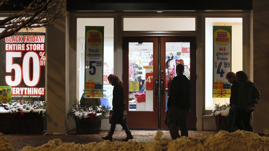 Shoppers in Freeport, Maine, pass by store windows advertising Black Friday deals after the stores opened their doors at midnight.