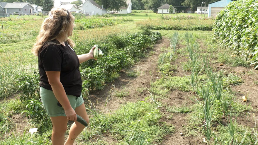 A woman shows her garden with many types of vegetables.