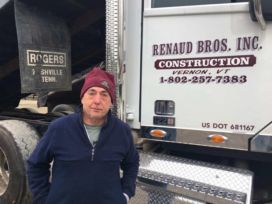 A man stands by a tractor trailer truck.