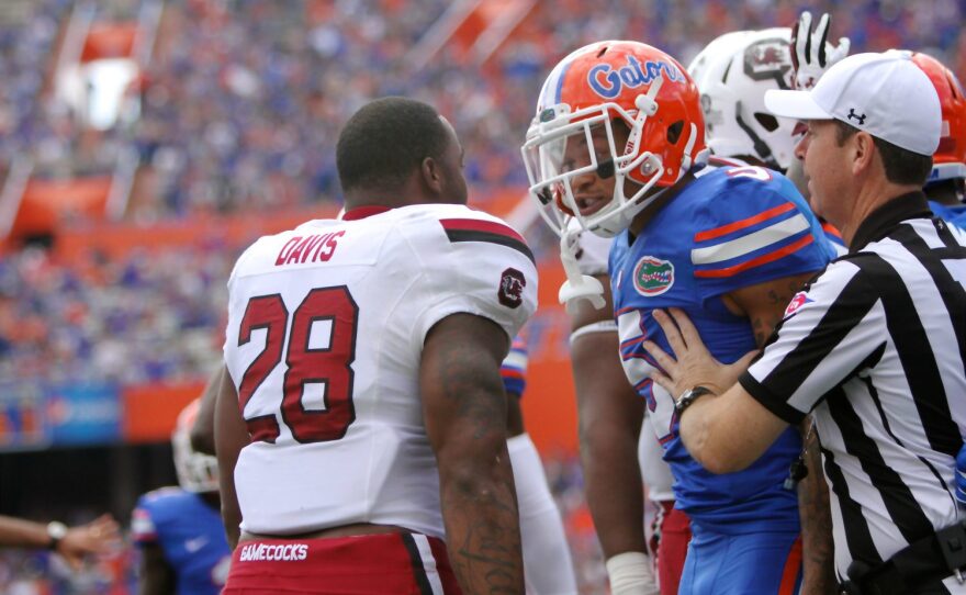 After having his helmet ripped off during the previous play, South Carolina’s Mike Davis and Florida’s Jalen Tabor exchange words.