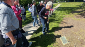 woman in flag sweater looks at a plaque on the ground