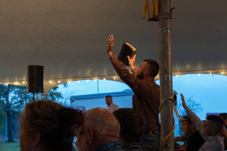 Devin Rose, pastor of Big Ridge Missionary Baptist Church, throws up his arms in praise of God at a tent revival in Oneida, Tenn. on Monday, Sept. 22, 2025. The revival was organized by Rose and other pastors in the area who feel that their community’s faith has faltered in recent years.