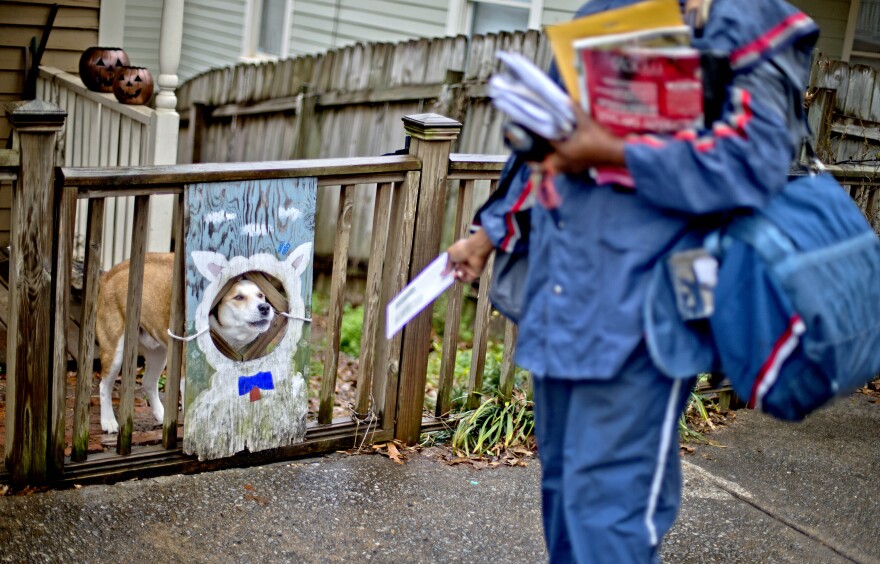 U.S. Postal Service letter carrier of 12 years, Jamesa Euler, encounters a barking a dog while delivering mail in the Cabbagetown neighborhood, Thursday, Feb. 7, 2013, in Atlanta. The financially struggling U.S. Postal Service wants to stop delivering mail on Saturdays but continue to deliver packages six days a week under a plan aimed at saving about $2 billion a year. 