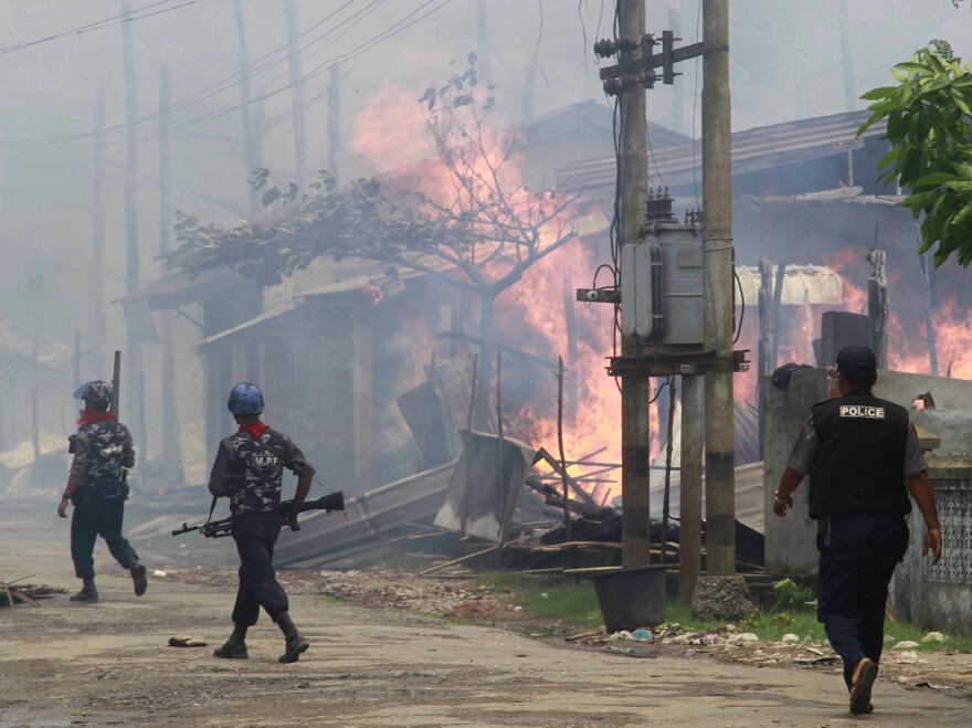Policemen in Myanmar walk toward burning buildings in the town of Sittwe, in the western part of the country, where Muslims and Buddhists have clashed recently.
