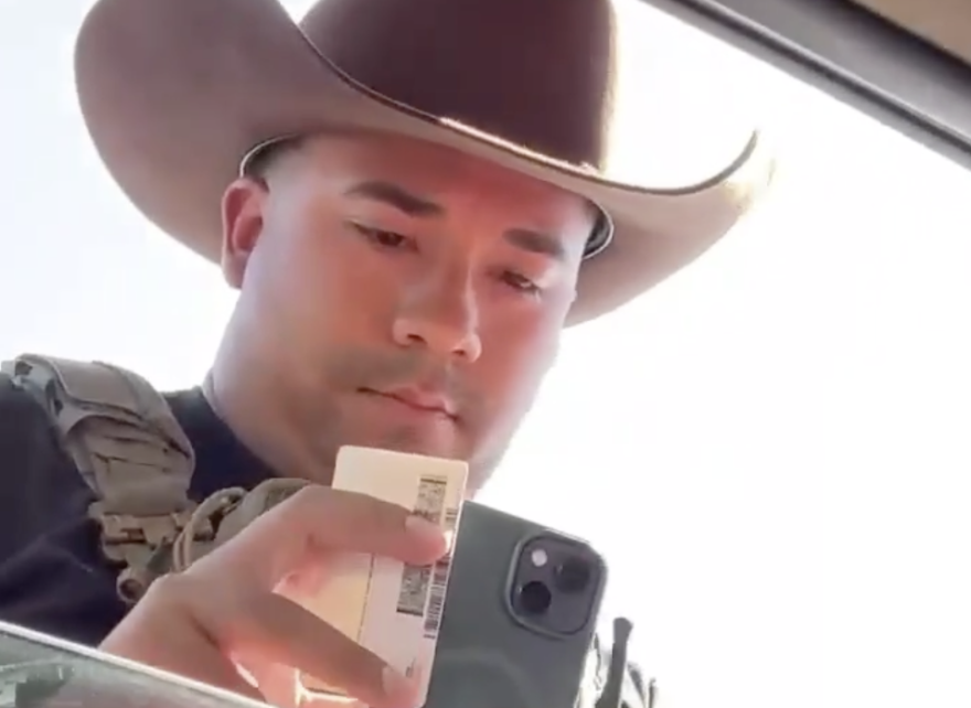 An unidentified Immigration and Customs Enforcement officer examines the driver's license of Dodge City, Kansas, resident Guadalupe Navarrete on Sept. 23, 2026. Navarrete was driving with her father Frank Duran. They were not detained.