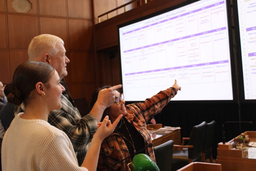 Rep. Paul Evans, D-Monmouth, (center), Chief of Staff Jennifer Randstrom-Smith (right) and Intern Emma Swartzfager (left) point at the candidate filing presentation.