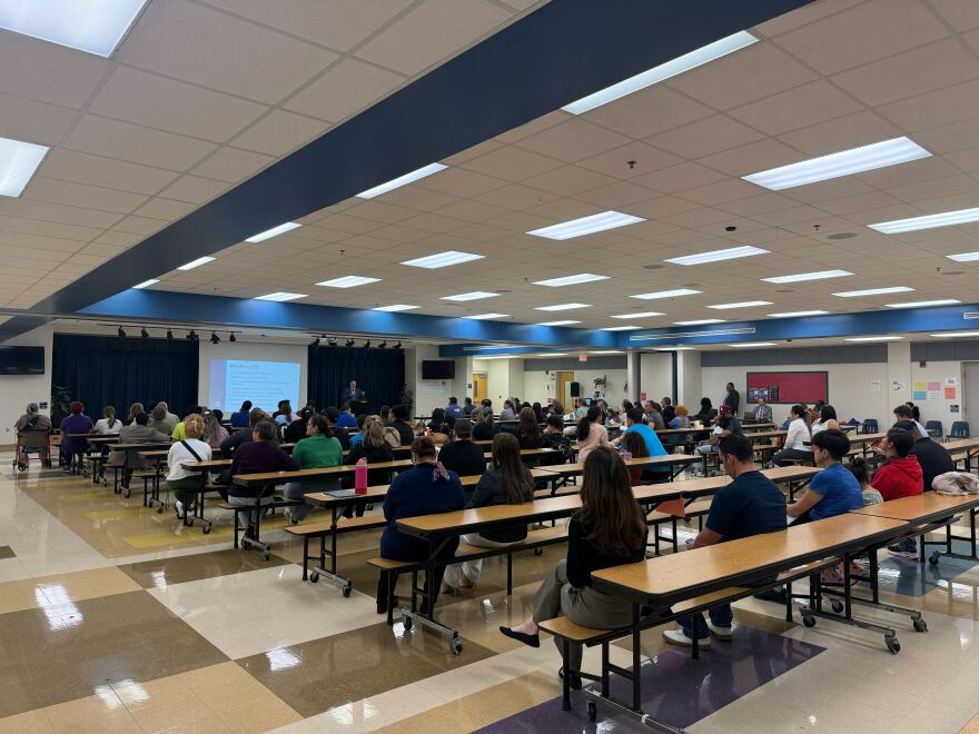 Close to a hundred people sit at cafeteria tables at McCoy Elementary School during one of the listening sessions from OCPS.