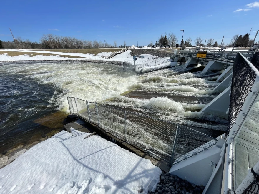 Water rushes through the spillway of a dam into an overflowing dam pool.