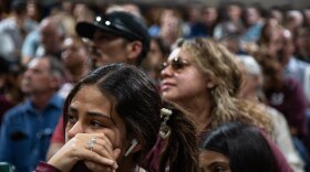 A young woman with her hand up to her cheek in the stands with other people