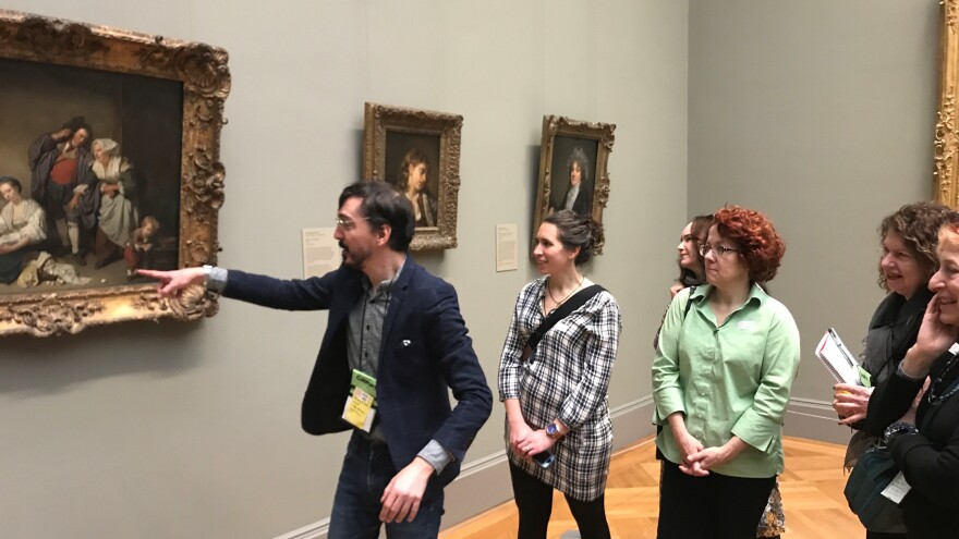 Angelis Nannos leads a tour to a 1756 oil painting by Jean-Baptiste Greuze, which seems to depict an innocuous scene of a young woman next to a basket of broken eggs while a young man is being scolded by the family matriarch. The subtext, however, is a little different, because the broken eggs symbolize the loss of the young woman's virginity.