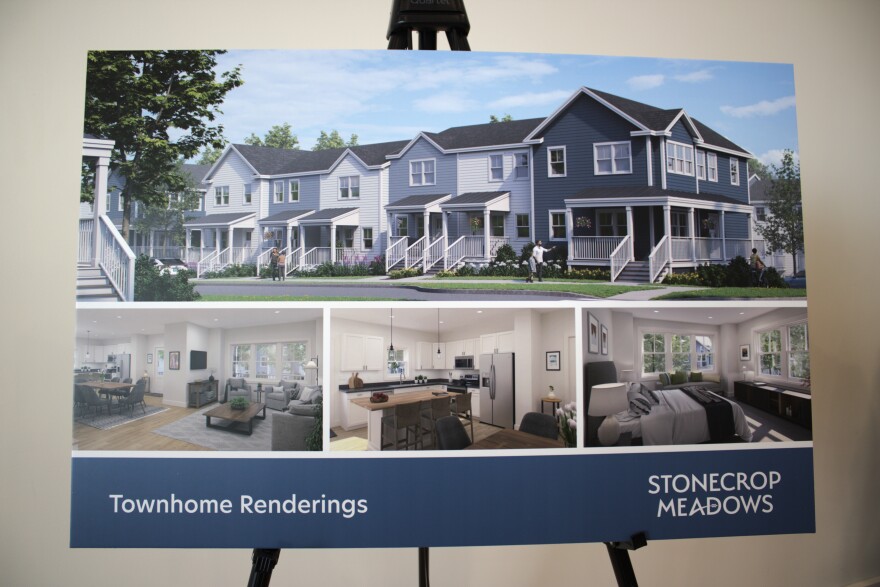 A poster on an easel shows townhomes and interior renderings