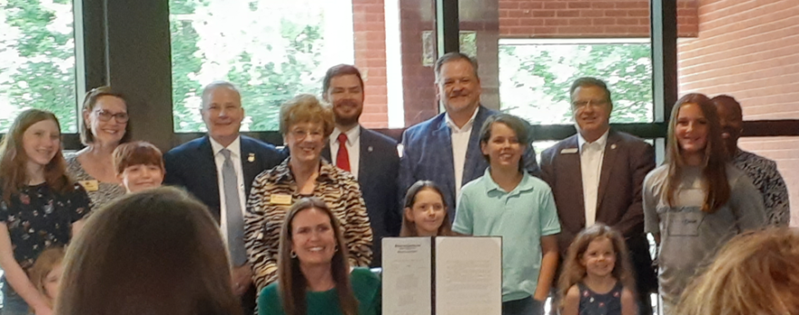 Gov. Sanders holds up SB458 after signing it into law. The bill will allow uniformed service personnel to apply for school vouchers.