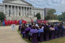 Onlookers and the family members of domestic violence victims stare at 47 silhouettes during Tuesday morning's ceremony. Each silhouette represented someone who died as a result of domestic violence; the lone purple silhouette represents unknown victims.