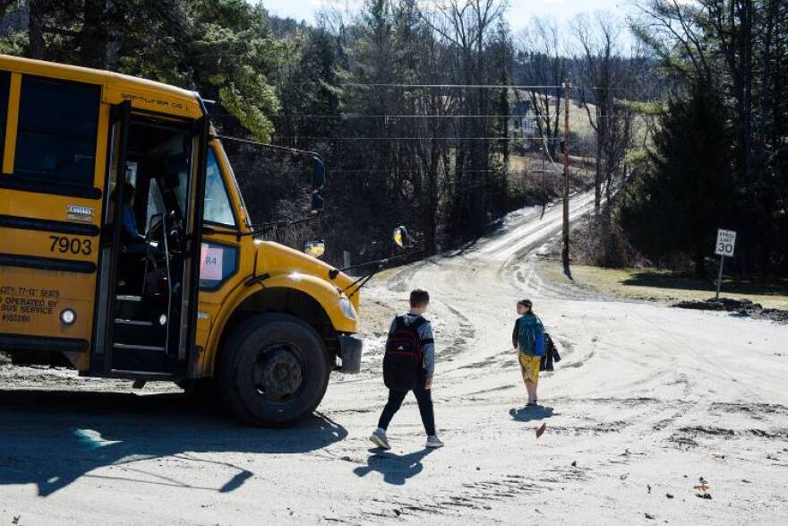 Dropped off at the transition from pavement to dirt on Back River Road in Royalton, Vt., Landon Cronan, 10, left, and his sister Josie, 8, begin their walk home on Monday, March 21, 2022. The White River Valley Schools limited bus transportation to paved roads through Monday to prevent further mud damage to dirt roads. (Valley News - James M. Patterson)