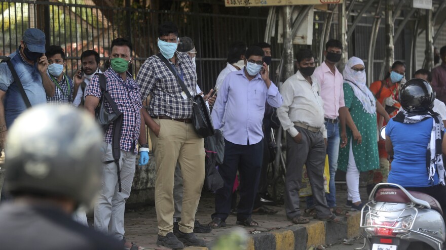 People wait for a bus in Mumbai, India, on Monday. India is reopening its restaurants, shopping malls and religious places in most of its states after a more than two-month lockdown even as the country continues to witness a worrying rise in new coronavirus infections.
