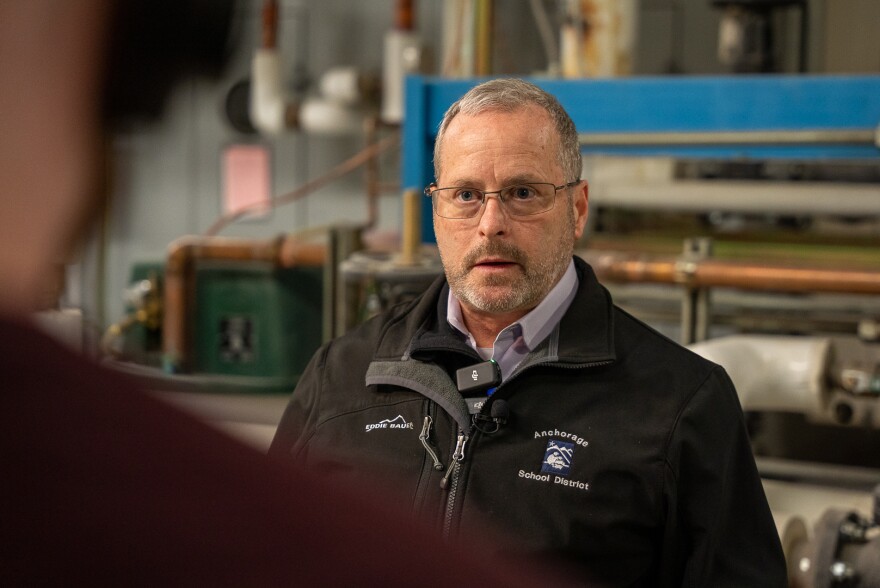 A guy standing in front of a major facility piping system.
