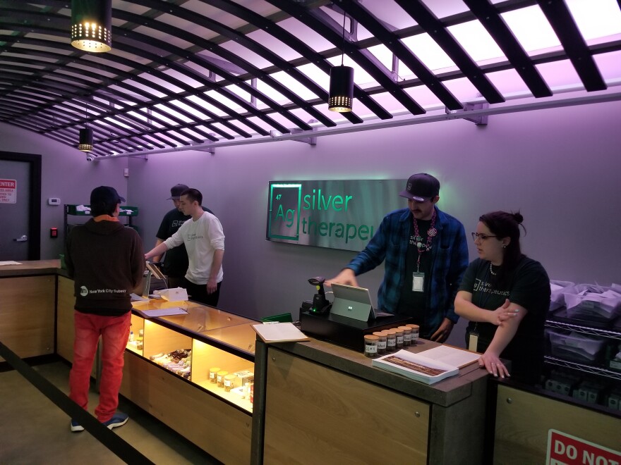 Store employees stand behind a low counter top in a room lit with purple light