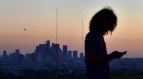 A man checks his cellphone while hiking in a Los Angeles park after sunset in Los Angeles, California.