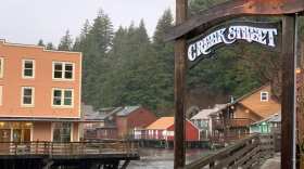 Rain falls in town next to a wooden sign that says "creek Street"
