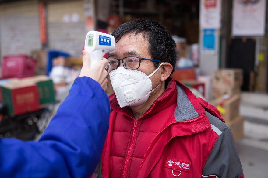 A courier gets his temperature checked. In Wuhan, individuals are required to get it checked twice a day.