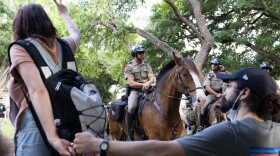 A protester holds up a peace sign as state troopers on horseback surround the demonstrators. 