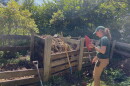 A woman stands at a compost pile.