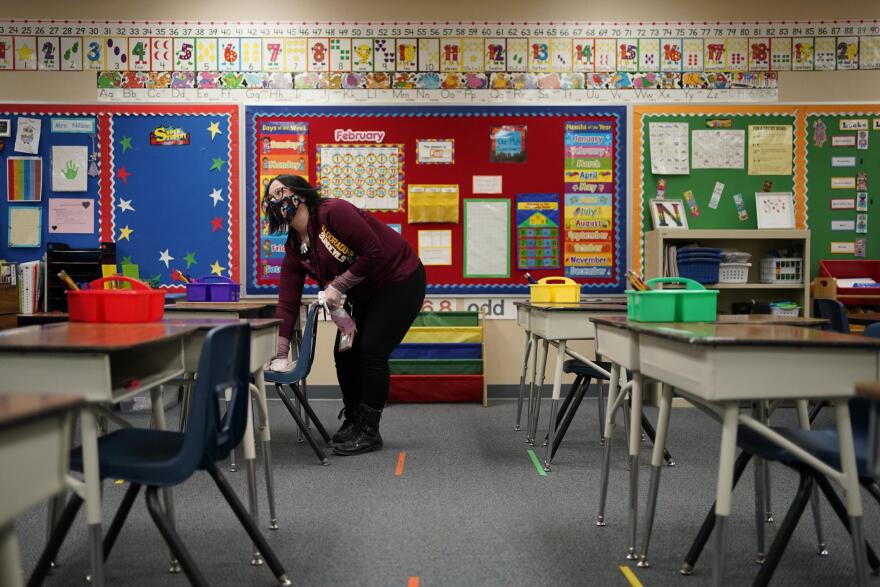 Tia Baker cleans a desk in a classroom during a media tour at Dorothy Eisenberg Elementary School, Thursday, Feb. 25, 2021, in Las Vegas.