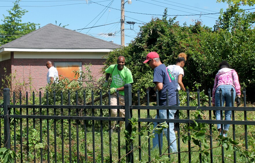 Volunteers clear brush from a community garden in the Jeff-Vander-Lou neighborhood June 24, 2017.