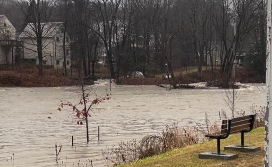 A photo of a bench sitting next to floodwaters. 