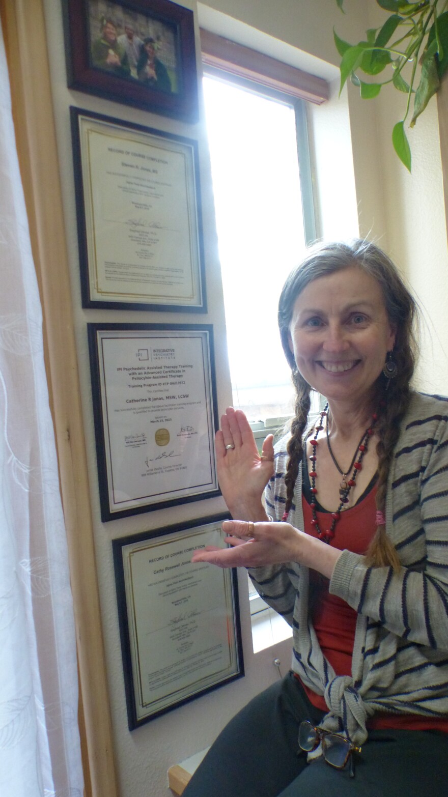 Cathy Jonas poses before certificates and licenses on the wall.