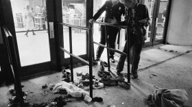 A security guard and an unidentified man look at an area where several people were killed as they were caught in a surging crowd entering Cincinnati's Riverfront Coliseum for a Who concert on Dec. 3, 1979.