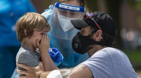 A young boy cries to his father after being tested for COVID-19 at the free testing being offered by the state in Chelsea Square. (Jesse Costa/WBUR)