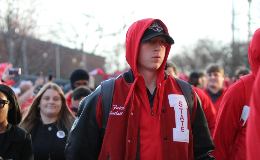 Fans and marching band members greet ISU football players and coaches