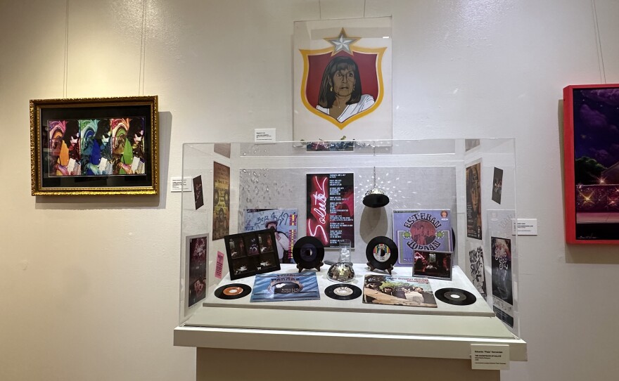 A display by Eduardo "Plata" Hernandez, member of the band Sexto Sol, features records, flyers and other items during the time that Saluté was open. The portrait "Lone Star (Azeneth)" by artist Rigoberto Luna hangs above.