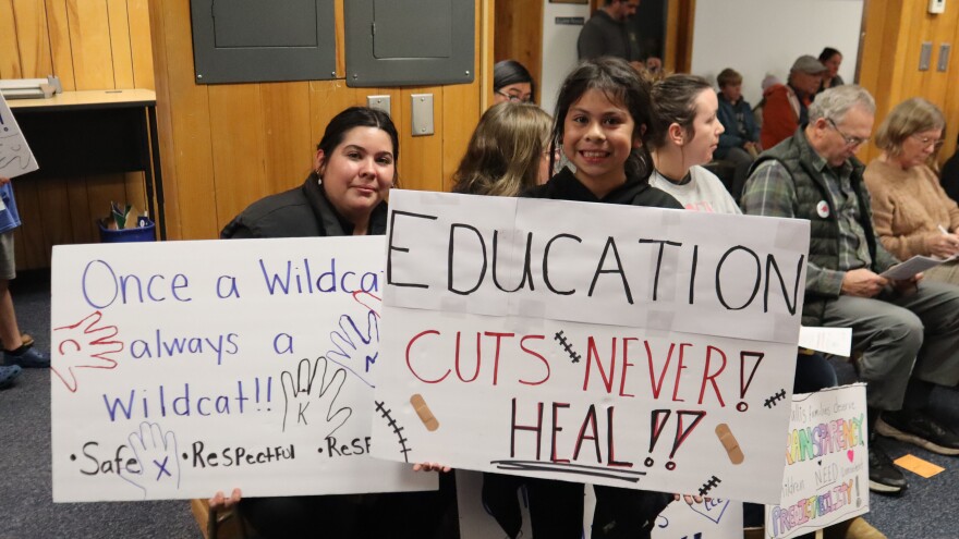 A mother and daughter hold signs at a Corvallis School Board meeting