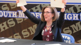Oregon Gov. Kate Brown holds up ceremonial copies of the bill she signed authorizing new funding for public education.