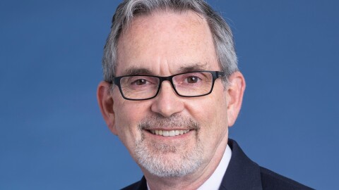 Dr. Richard Dart, Director of the Rocky Mountain Poison Center. He has light silver-gray hair and beard, and wears a dark blue suit jacket with a light pink shirt and blue tie.