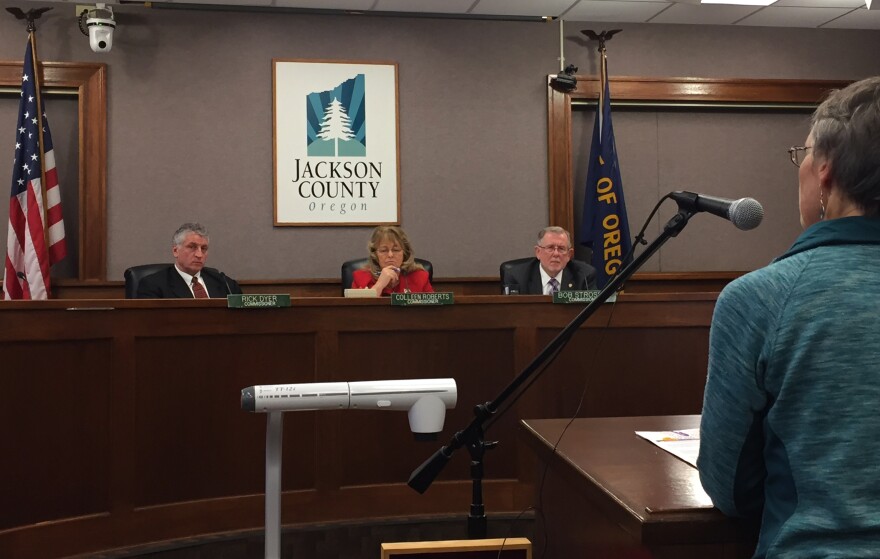 Image of councilmembers listening to woman speak at a microphone.